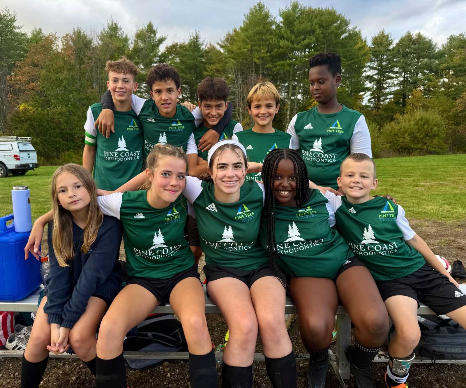 Pine Tree Academy middle school soccer players in green jerseys posing together on the team bench after their 11–7 home victory over Living Waters Christian School on October 14, 2026