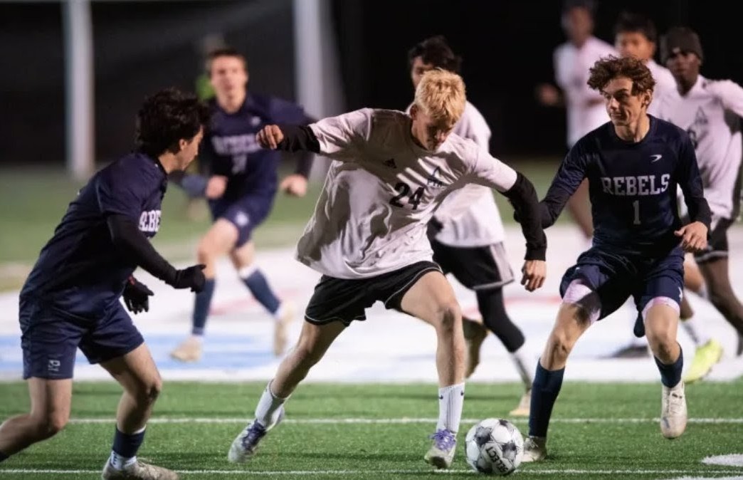 Pine Tree Academy's Collin Verrill, number 24 in white, attacking between Richmond defenders under the lights